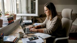 Uspešna poslovna ženska si doma za pisalno mizo premišljeno oblikuje strategijo za digitalni nastop.